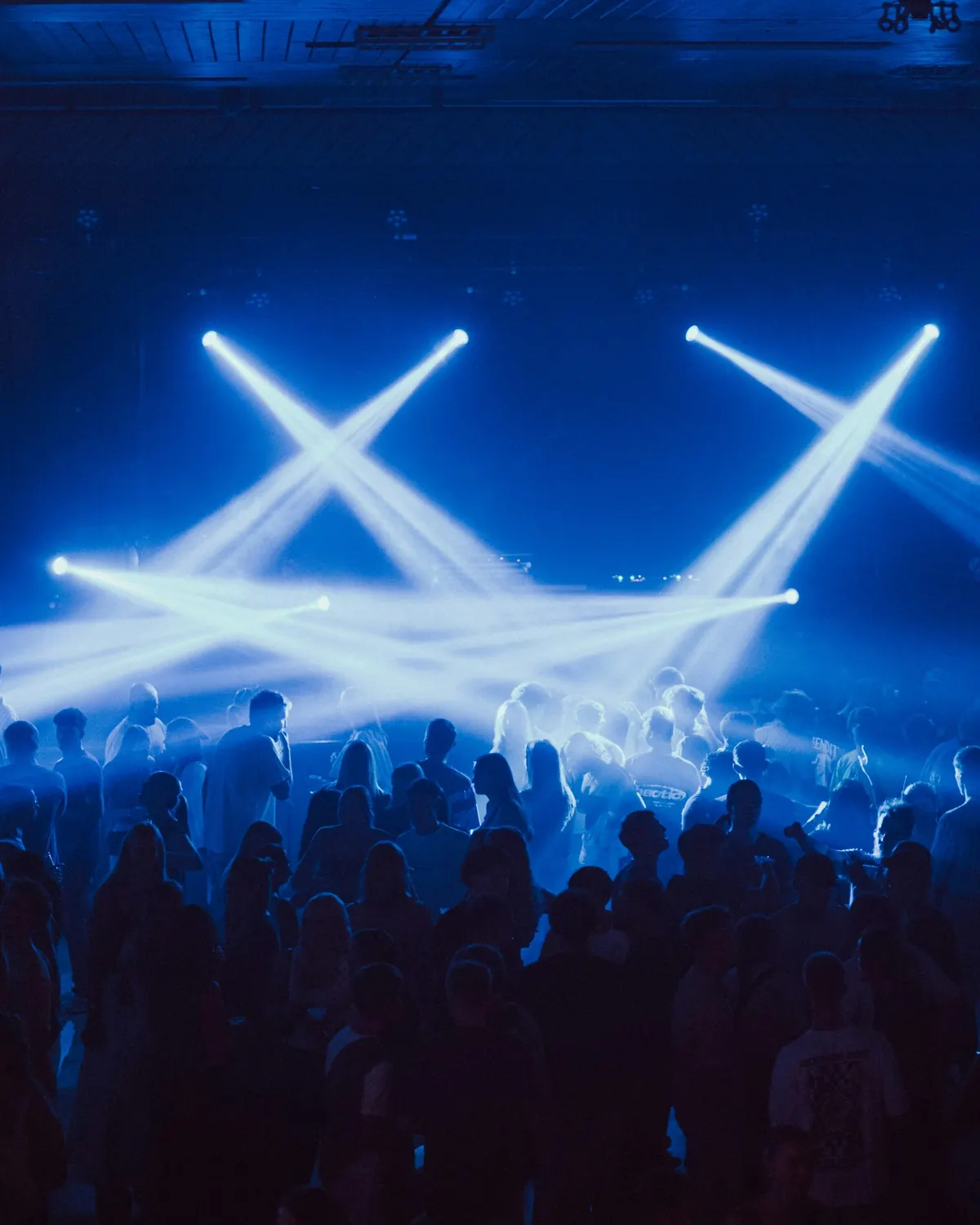 A concert crowd under crossing blue stage lights